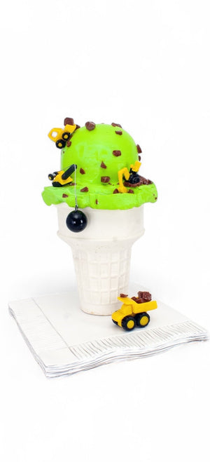 Chocolate Party glass sculpture with a bright green ice cream scoop, brown chocolate pieces, and miniature yellow construction vehicles atop a white cone