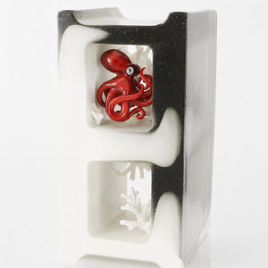 Guest House glass sculpture featuring a red octopus and white coral inside a black-and-white cast glass cinder block.

