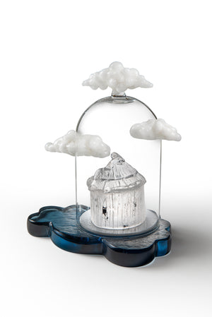 Look Out...side glass sculpture featuring a small white round building beneath a clear dome, surrounded by white clouds on a blue cloud-shaped base.
