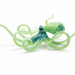 Mint-green glass octopus sculpture with blue spotted details and long tentacles curling into loops on a white background.

