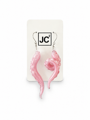 Asymmetrical pink glass tentacle earrings with pale suckers, one long and one curled, on silver hooks displayed on a white JC2 card.
