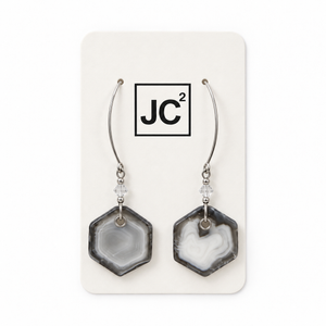 Smoke Rings earrings with gray and white hexagonal glass murrini pendants on long sterling silver ear wires, displayed on a white JC2 card.

