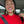 Smiling woman in a red sweater wearing asymmetrical yellow-green glass tentacle earrings, showing their length when worn.
