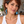 Woman with short auburn hair and a blue streak wearing a white tank top and asymmetrical sky-blue glass tentacle earrings with white suckers.
