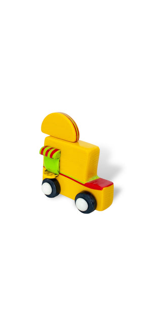 The Primaries glass taco truck sculpture with a yellow body, red accents, a striped serving awning, dark wheels, and a taco-shaped roof sign.
