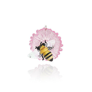 Glass ornament featuring a yellow and black bee with clear wings on a translucent pink flower.
