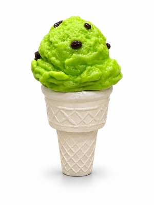 Glass mint chocolate chip ice cream sculpture with a bright green textured scoop, dark brown chips, and an ivory waffle cone on a white background.